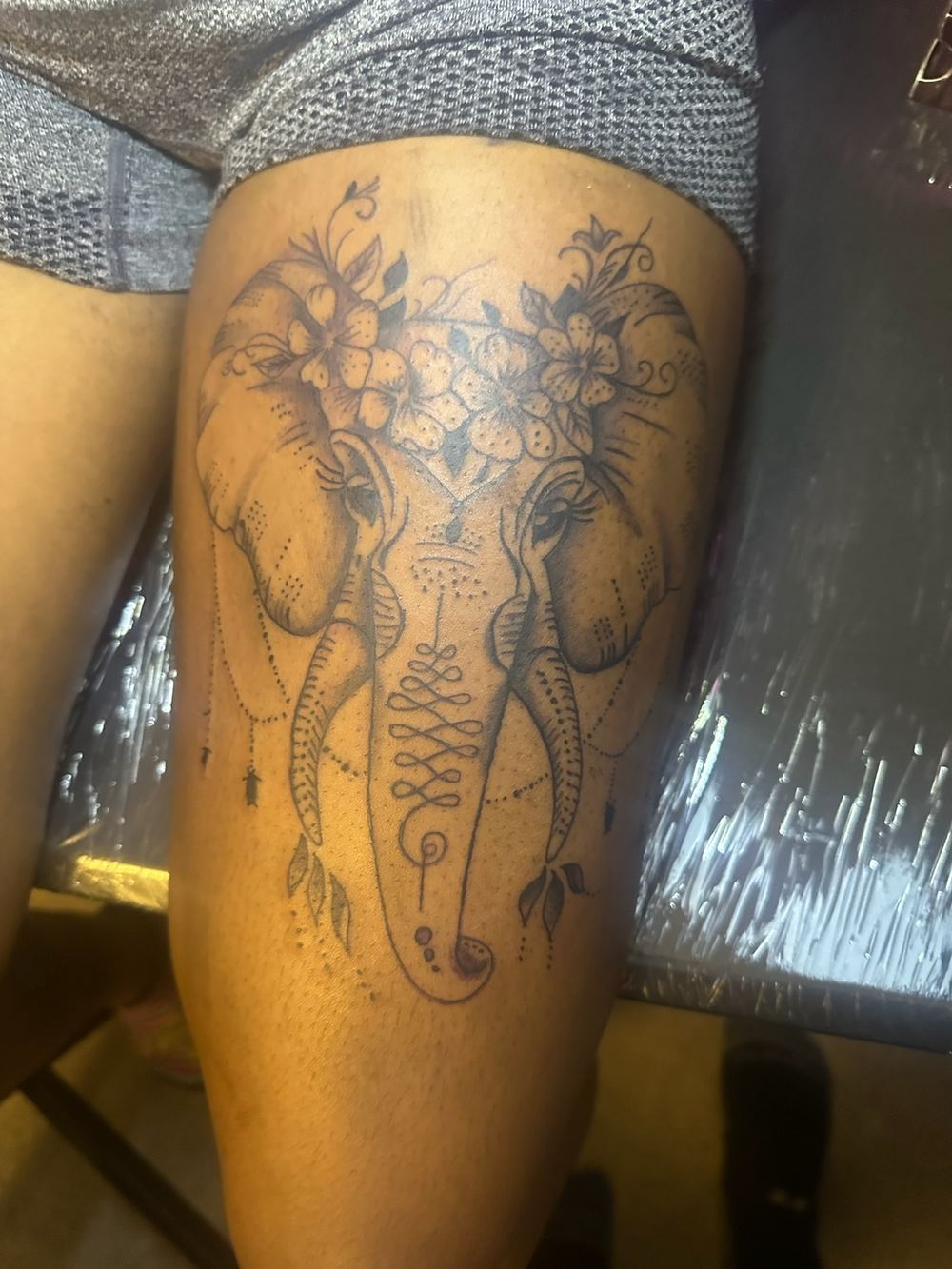 Elephant with floral crown fine line thigh tattoo